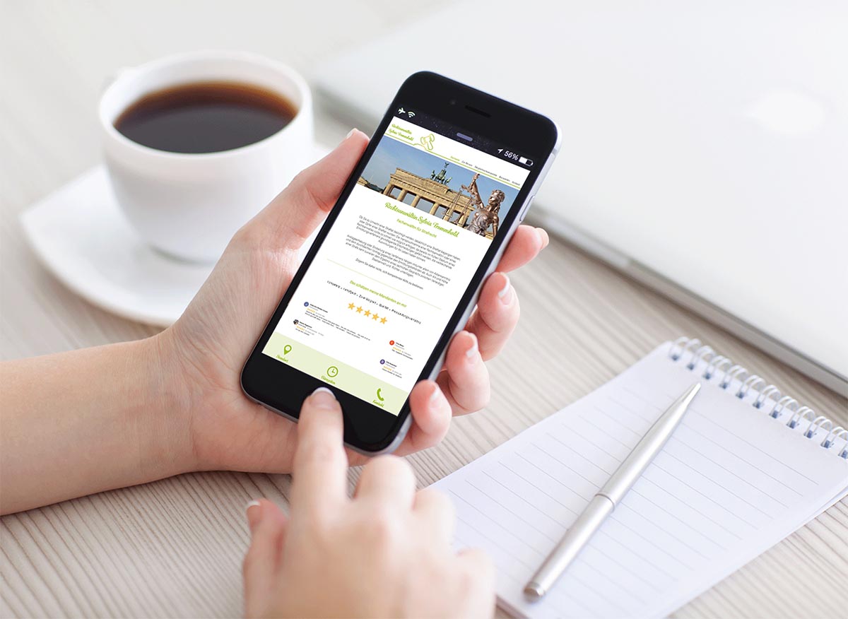 Smartphone mit der Kanzlei-Website neben einer Tasse Kaffee
